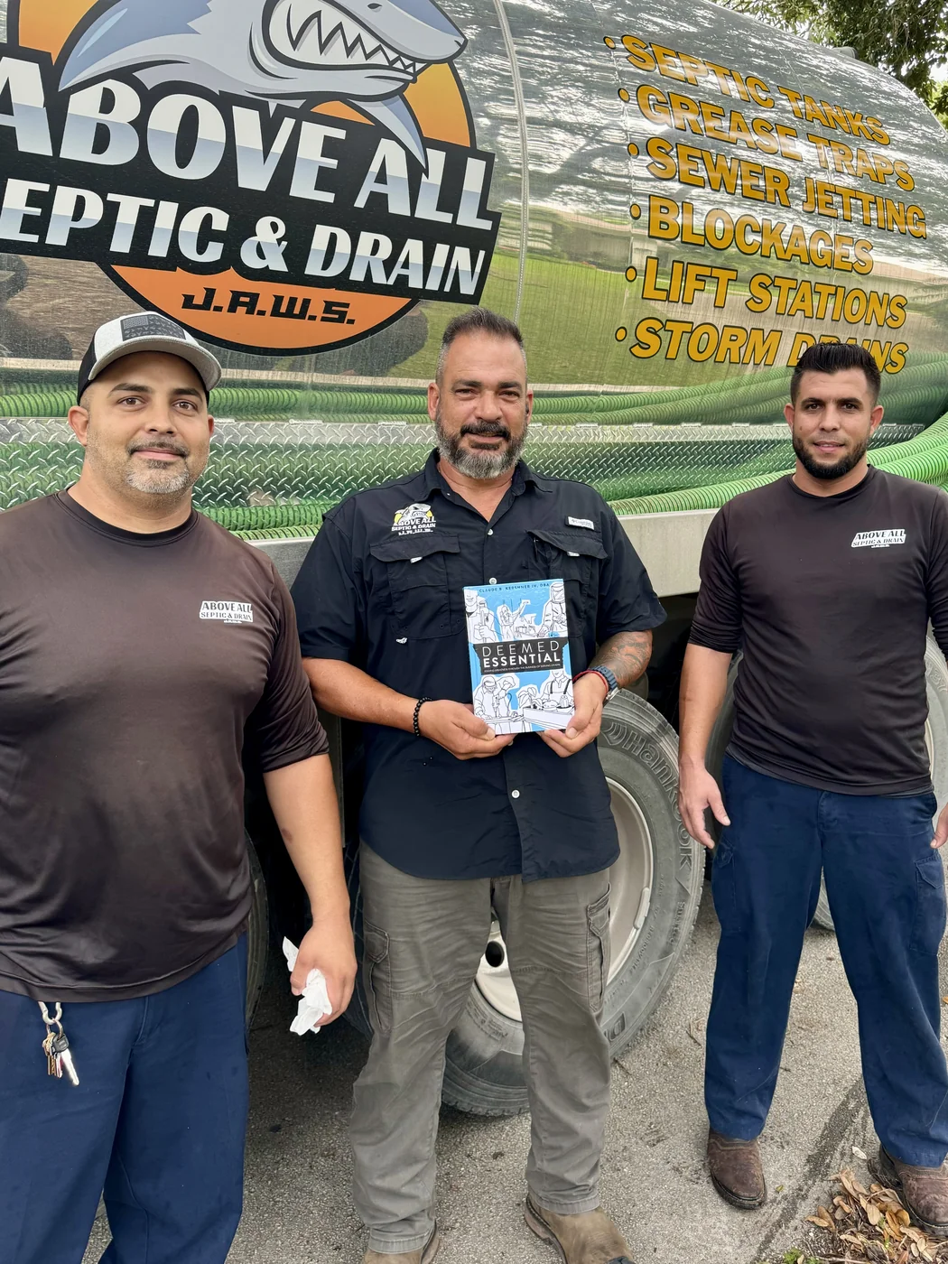 Service professionals holding a copy of Deemed Essential in the field